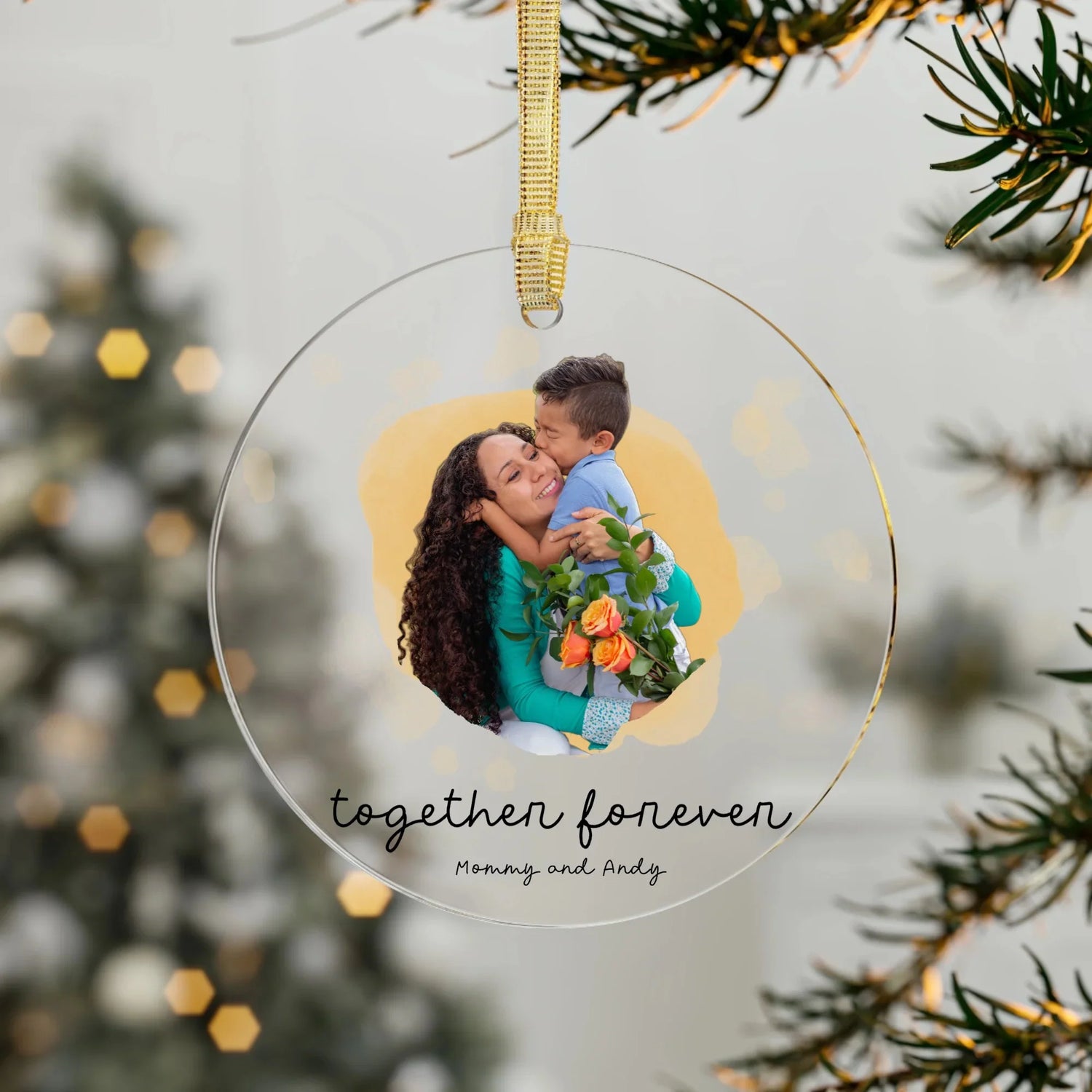 Printed personalized acrylic Christmas ornament hanging from a Christmas tree.